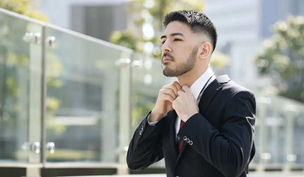 Je ne sais pas quoi faire de ma vie : la solution 5 Un homme en costume ajuste sa cravate, incertain et réfléchissant à ses choix de vie.