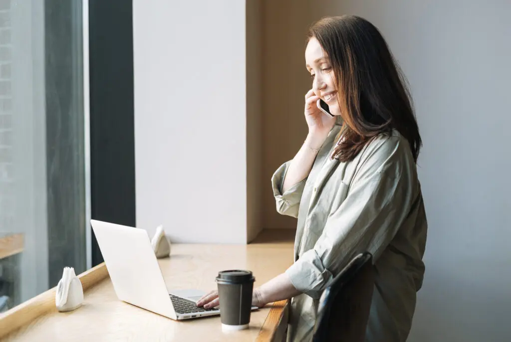 Créer son auto-entreprise - Tutoriel complet pour débutant 8 Une femme créant son auto-entreprise en suivant un tutoriel complet pour débutant, assise à un bureau avec un ordinateur portable et une tasse de café.