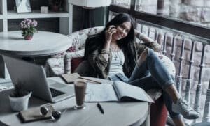 Une femme assise dans un fauteuil avec un ordinateur portable et un téléphone, en train de créer son auto-entreprise.