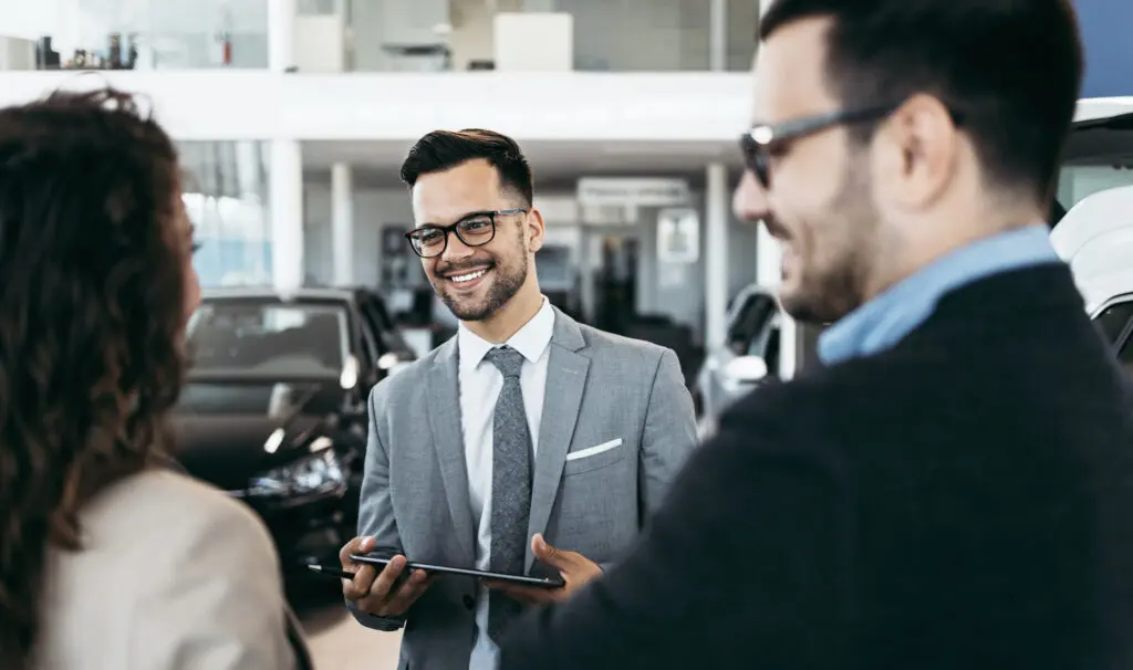 Showroom : Comment peut il augmenter vos ventes ? 2 Un homme et une femme discutent dans un showroom de voitures.