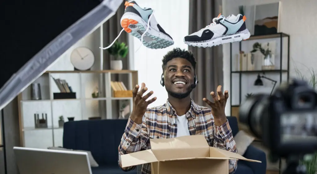 Showroom : Comment peut il augmenter vos ventes ? 4 Un homme présente une boîte de chaussures dans une salle d'exposition, illustrant comment elle peut augmenter vos ventes.