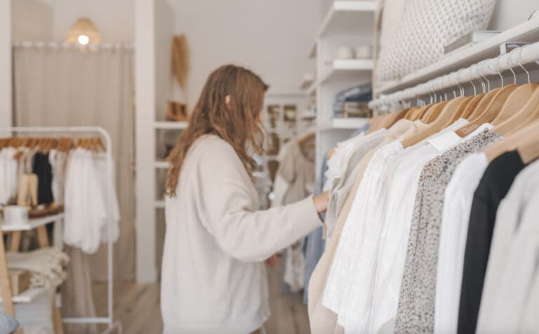 Une femme parcourt des vêtements dans une salle d'exposition et explore comment cela peut stimuler les ventes.