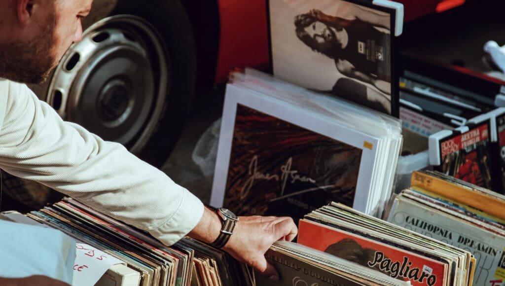 Un homme cherchant des disques dans un marché aux puces à Sabradou.
