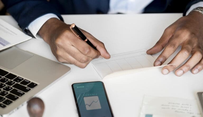 Un homme en costume écrit sur une feuille de papier dans un tutoriel étape par étape sur comment remplir un chèque.