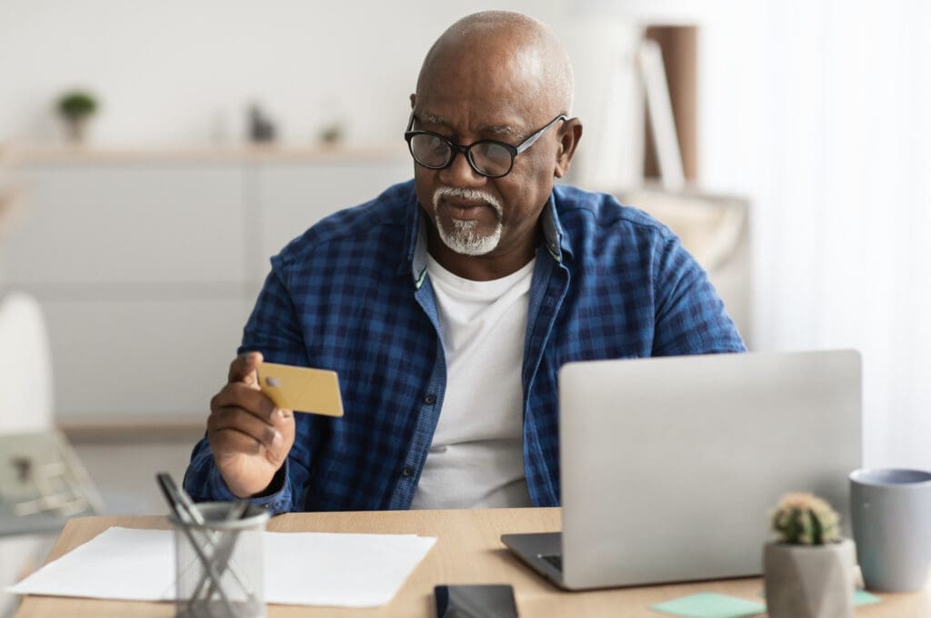 Un homme âgé utilisant Shopmium, une application de cashback qui rembourse les achats, assis devant son ordinateur.