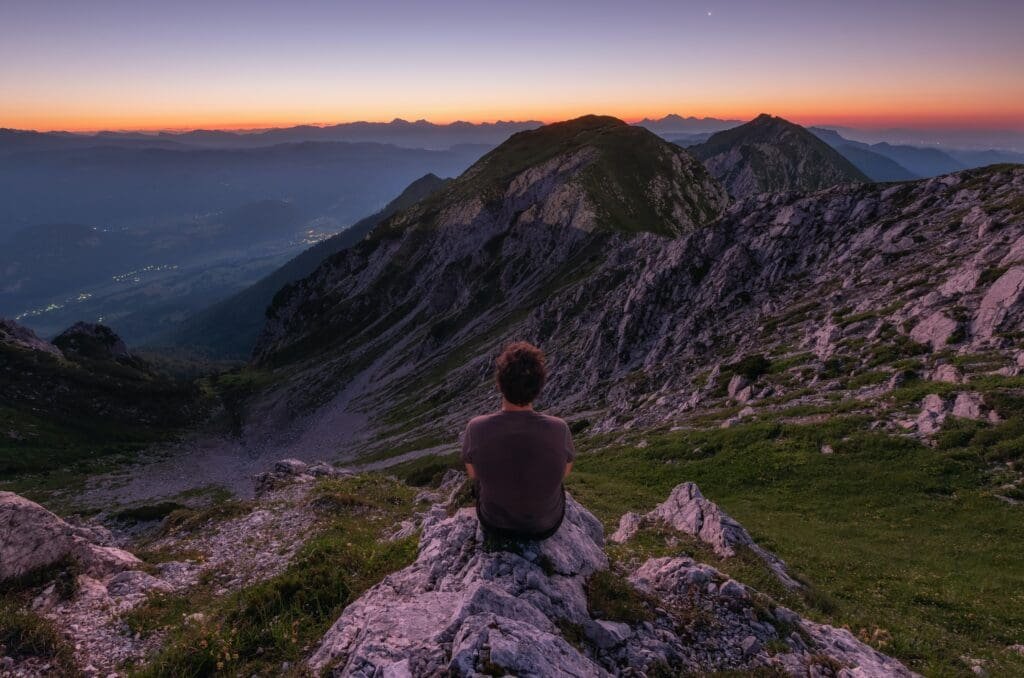 Un homme à l’esprit paisible assis au sommet d’une montagne au coucher du soleil.