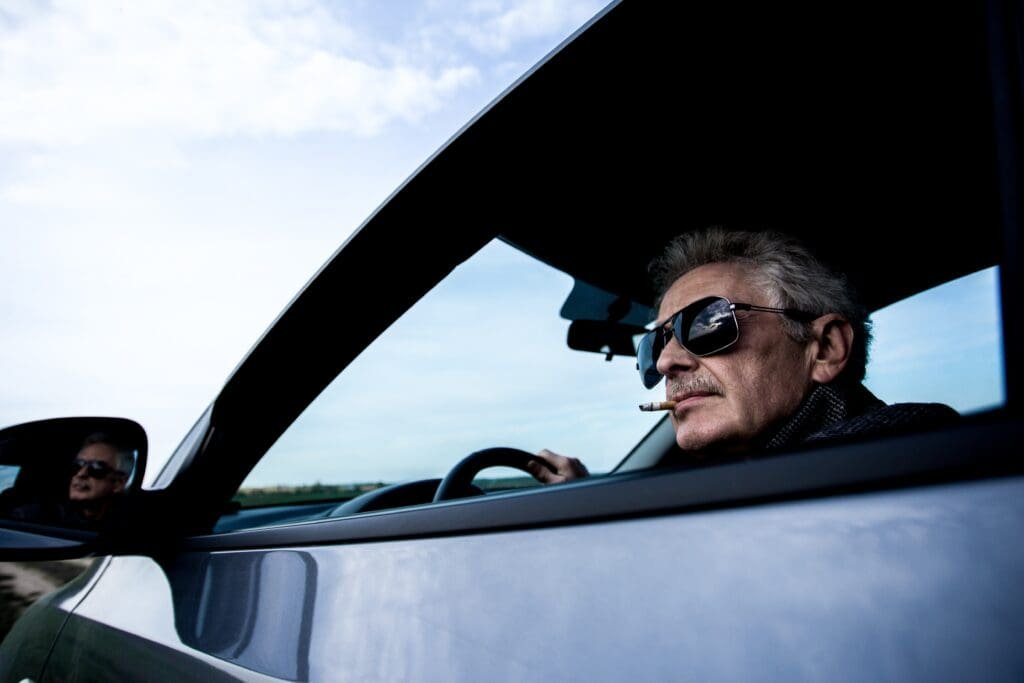 Un homme portant des lunettes de soleil conduit une voiture.