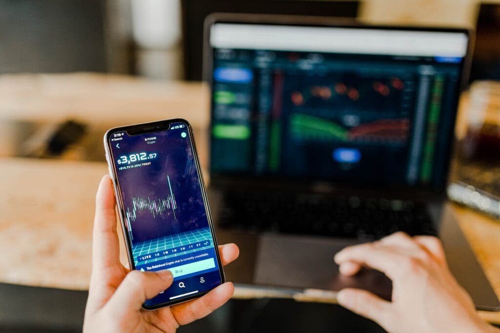 Intérêts Composés : Qu'est ce que c'est et comment optimiser 3 Une personne optimisant les intérêts composés avec une application de trading sur son téléphone.