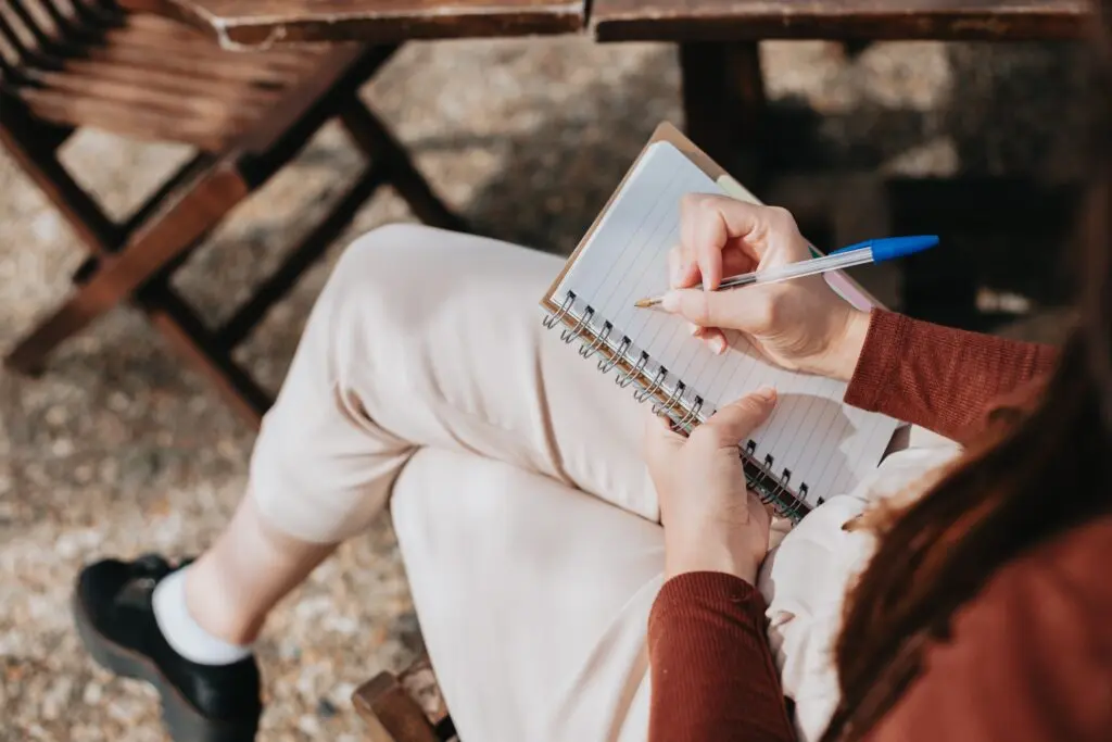 La Masse Dormante : 90% de vos clients ne vous disent rien 1 Une femme assise sur un banc écrit dans un cahier, tandis que La Masse Dormante observe des clients passifs.