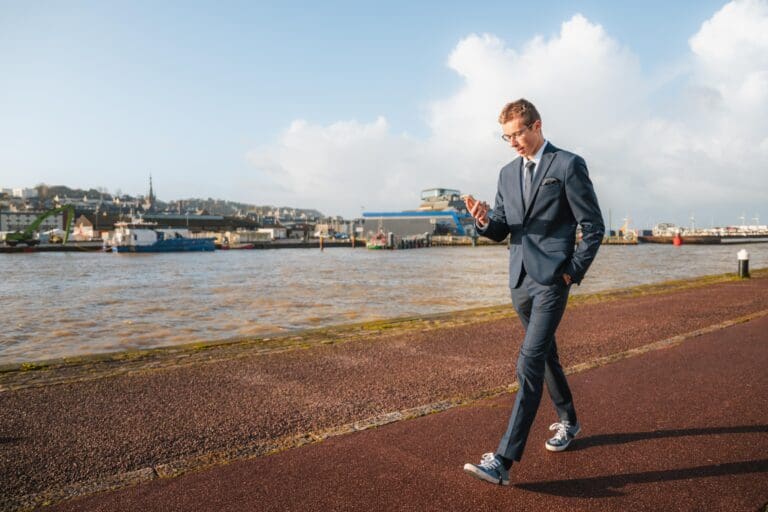 Un homme d’affaires utilisant Sweatcoin marche sur un chemin près d’une rivière.
