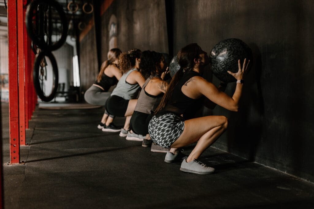 Un groupe de femmes faisant des squats dans une salle de crossfit, se concentrant sur l'EMS et lançant leur entreprise de fitness.