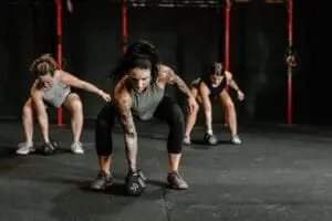 Un groupe de femmes faisant des exercices de kettlebell dans une salle de sport crossfit. Mots-clés : Lancer Son Activité