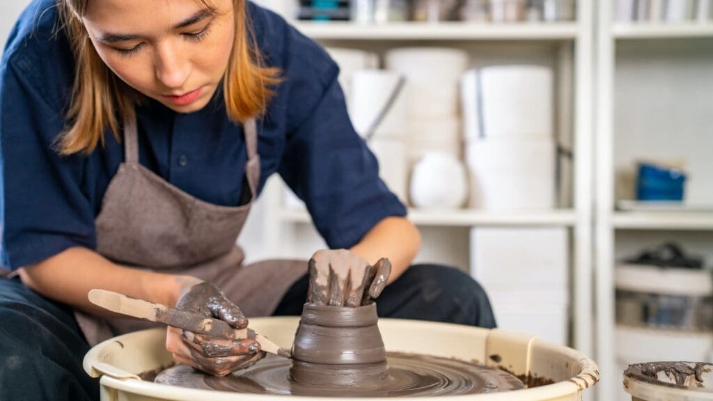 Une femme fabrique de la poterie sur un tour de potier.