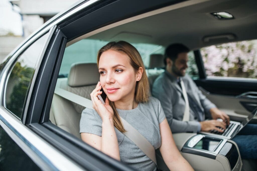 Une femme parle au téléphone alors qu’elle est assise sur le siège arrière d’une voiture, ce qui lui permet de gagner facilement de l’argent.