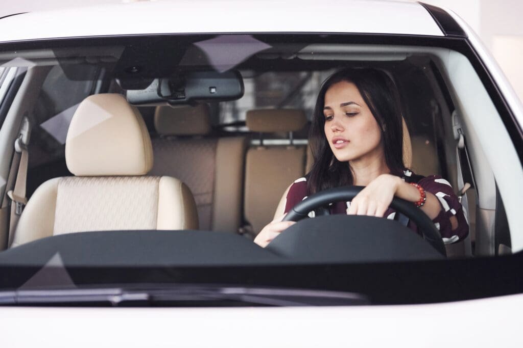 Une femme assise au volant d'une voiture.