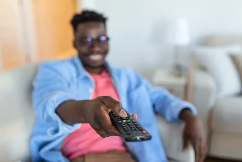 La Masse Dormante : 90% de vos clients ne vous disent rien 2 Un homme assis sur un canapé avec une télécommande.