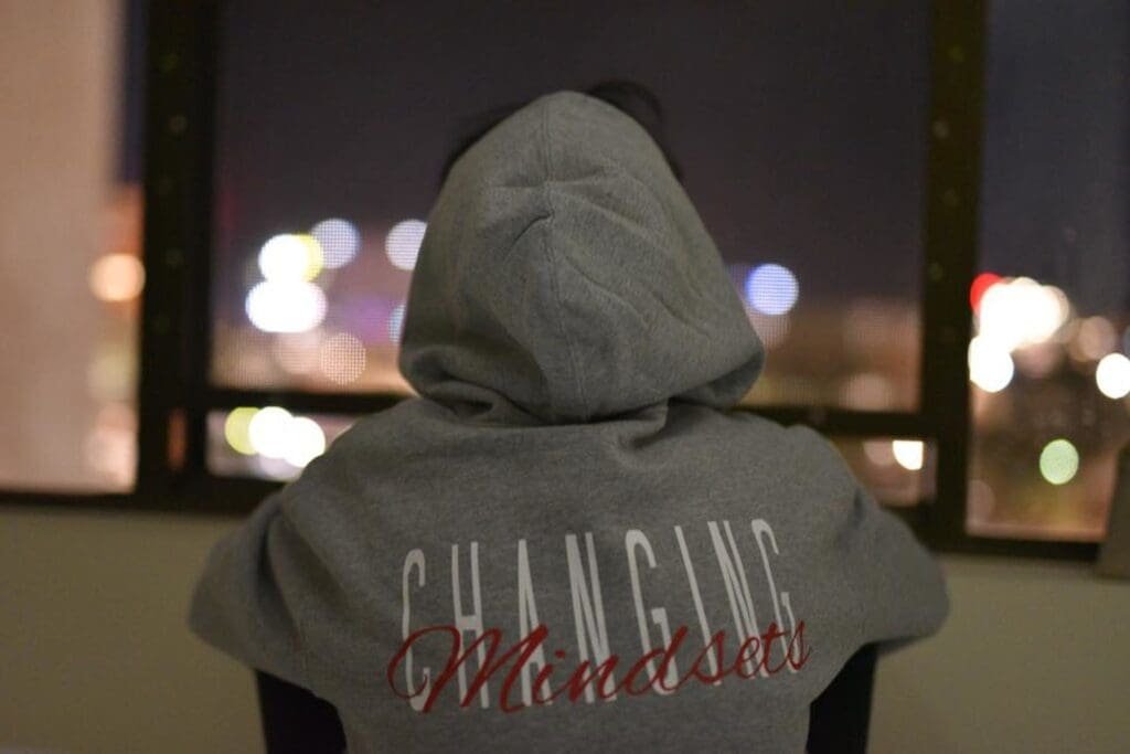 Le dos d'une femme portant un sweat à capuche gris sur lequel est imprimée l'expression « changer de mentalité ».