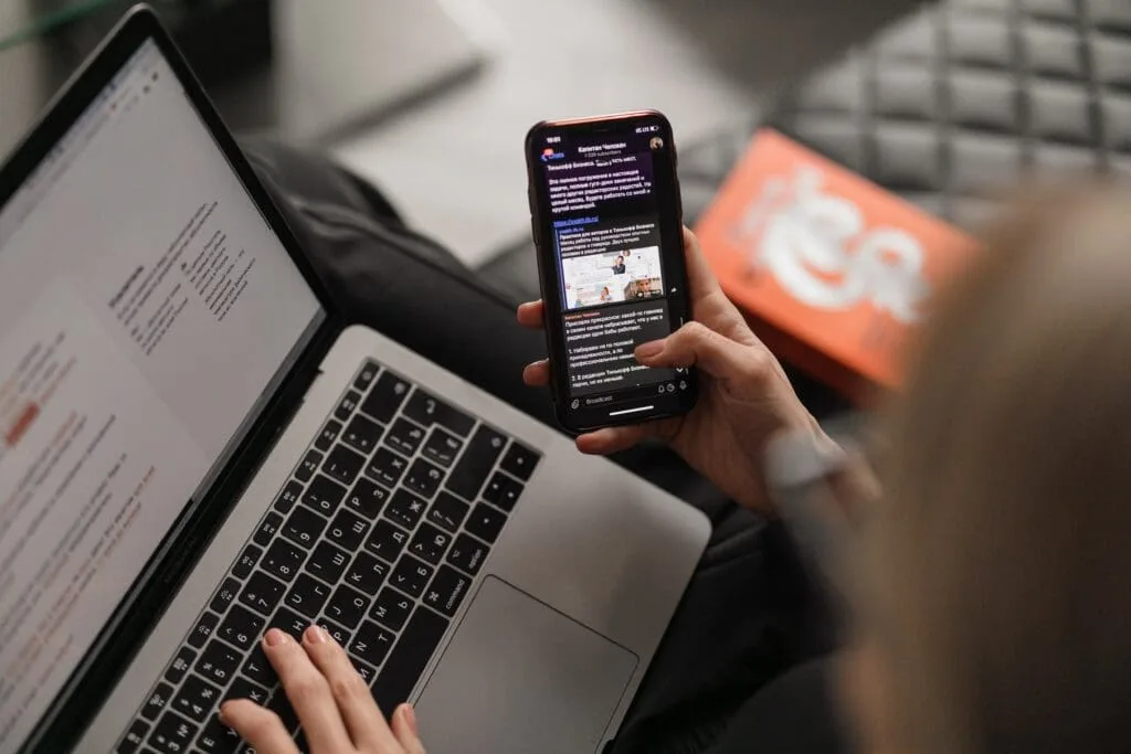Comment WhatsApp Peut Aider à Augmenter vos Clients en E-commerce 4 Une femme multitâche avec un smartphone et un ordinateur portable.