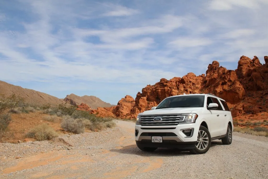 Gagner de l'Argent en Louant Sa Voiture facilement 1 Une Ford Expedition blanche garée sur un chemin de terre, facilement.